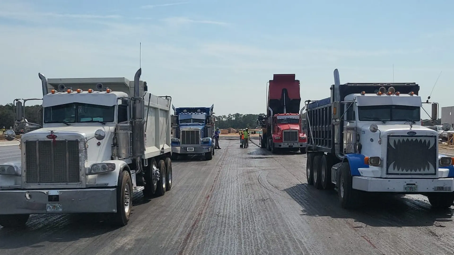 Tri-axle dump trucks lined up on a Florida paving project