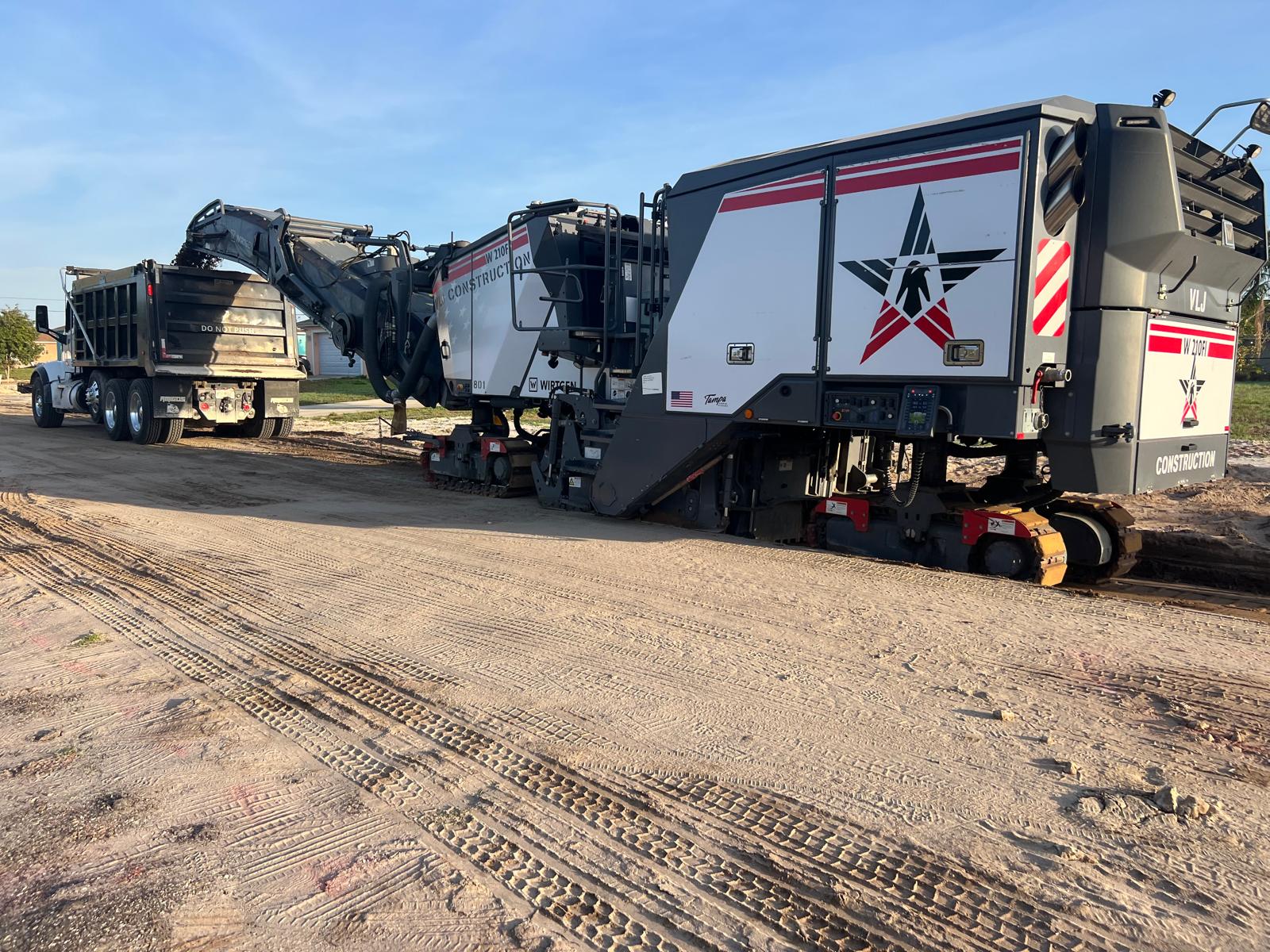 VLJ Construction asphalt milling machine transferring milled material into a dump truck on a job site near Tampa, Florida

